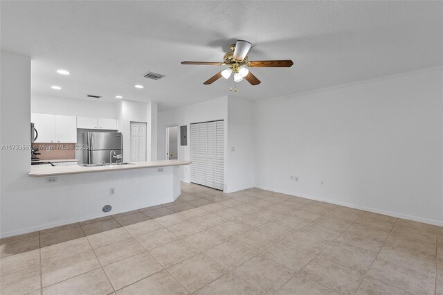 kitchen featuring sink, stainless steel fridge, white cabinets, ceiling fan, and kitchen peninsula