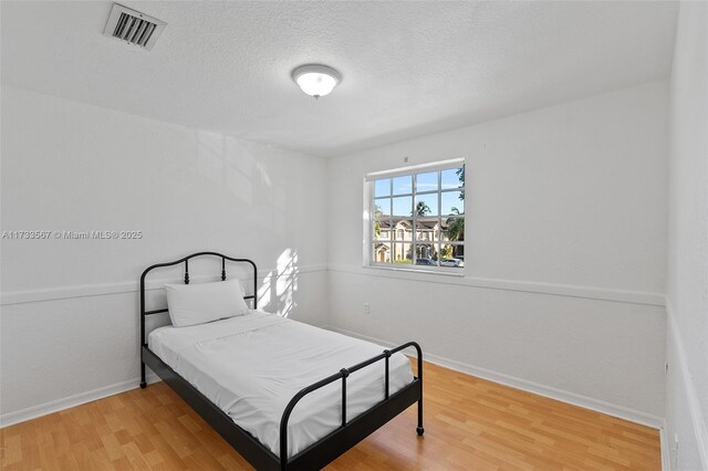 bedroom featuring hardwood / wood-style flooring and a textured ceiling