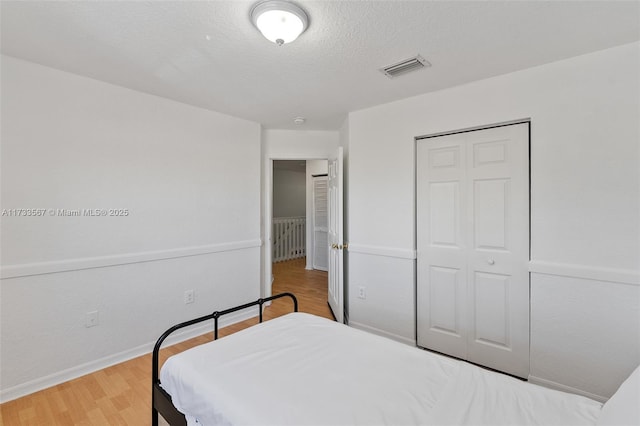 bedroom with hardwood / wood-style floors, a textured ceiling, and a closet