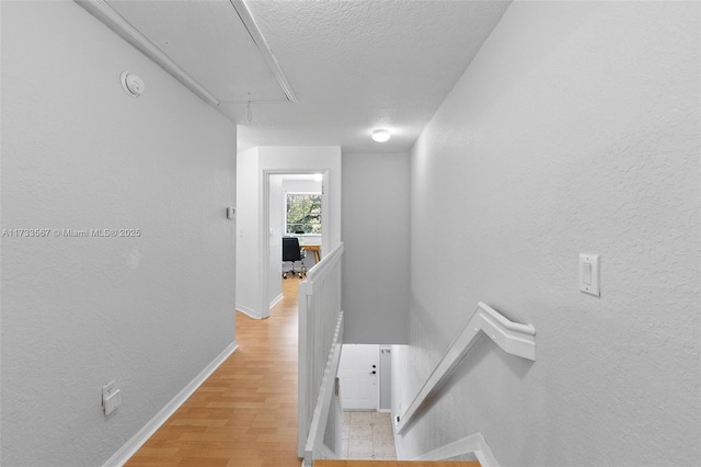 corridor featuring a textured ceiling and light wood-type flooring