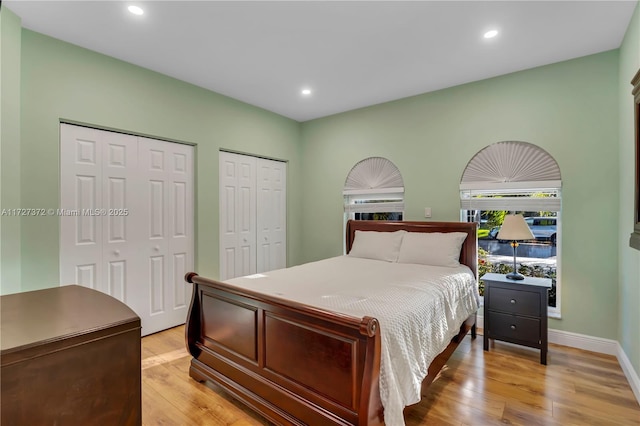 bedroom featuring multiple closets and light hardwood / wood-style flooring