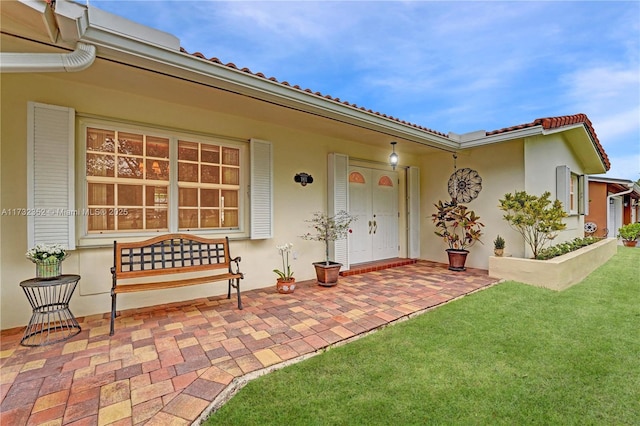 entrance to property featuring a patio area and a lawn