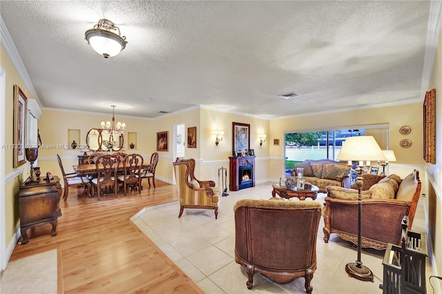 living room with ornamental molding, a chandelier, a textured ceiling, and light wood-type flooring