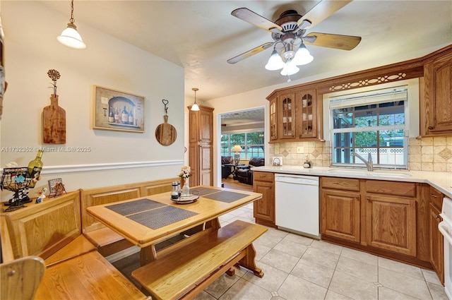 kitchen featuring sink, decorative light fixtures, light tile patterned floors, white dishwasher, and backsplash