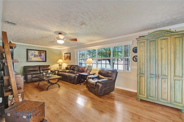 living room with crown molding, a textured ceiling, brick wall, and light wood-type flooring