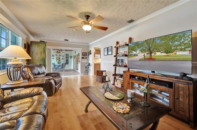 living room featuring crown molding, ceiling fan, a textured ceiling, and light wood-type flooring