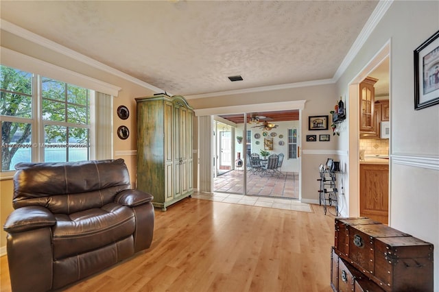 living room featuring ornamental molding, light hardwood / wood-style floors, and a textured ceiling