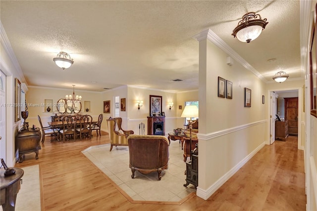 living room with crown molding, a chandelier, light hardwood / wood-style flooring, and a textured ceiling