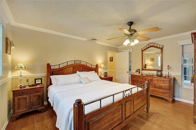 bedroom featuring hardwood / wood-style flooring, ornamental molding, a textured ceiling, and ceiling fan