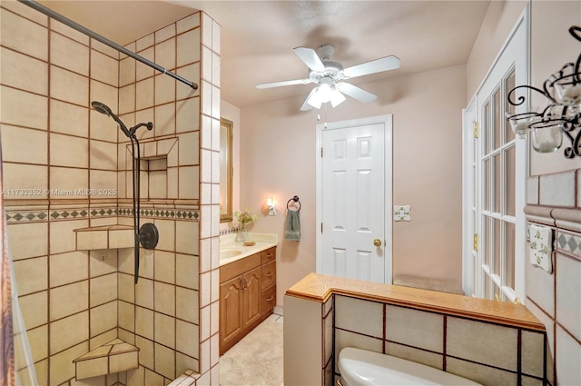 bathroom featuring a tile shower, vanity, toilet, and ceiling fan