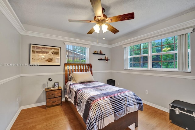 bedroom with crown molding, ceiling fan, a textured ceiling, and light wood-type flooring