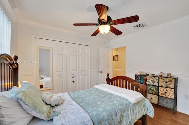 bedroom with wood-type flooring, a textured ceiling, ornamental molding, a closet, and ceiling fan