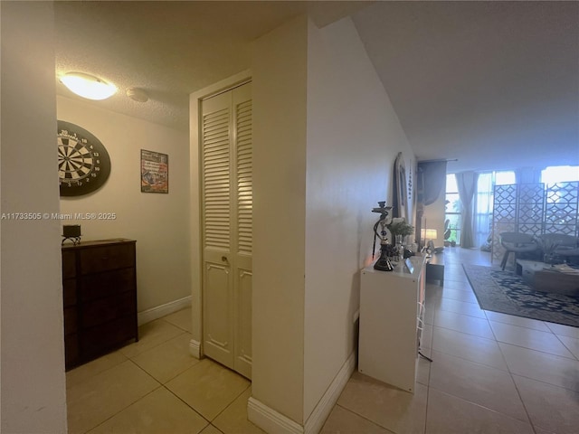 hallway with a textured ceiling and light tile patterned flooring