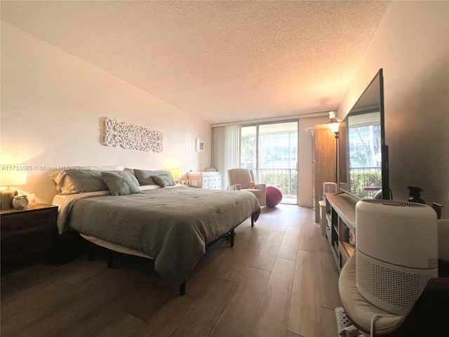 bedroom with wood-type flooring, access to outside, floor to ceiling windows, and a textured ceiling