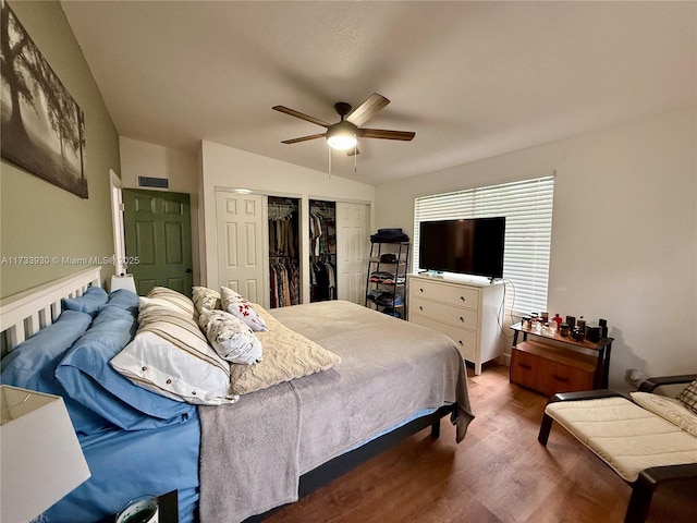 bedroom with multiple closets, vaulted ceiling, dark hardwood / wood-style floors, and ceiling fan