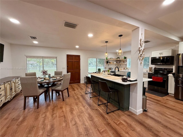 kitchen featuring white cabinetry, a kitchen bar, hanging light fixtures, black range with electric cooktop, and stainless steel refrigerator with ice dispenser