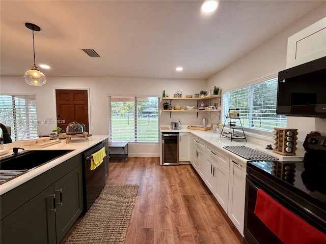 kitchen featuring pendant lighting, white cabinetry, wine cooler, black appliances, and light hardwood / wood-style floors