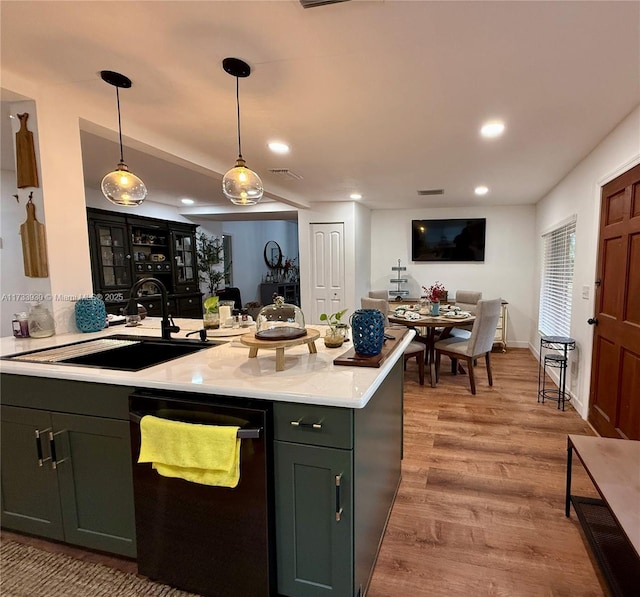 kitchen with dishwasher, sink, hanging light fixtures, green cabinets, and light hardwood / wood-style floors