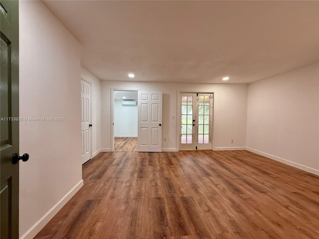 empty room with hardwood / wood-style flooring, an AC wall unit, and french doors