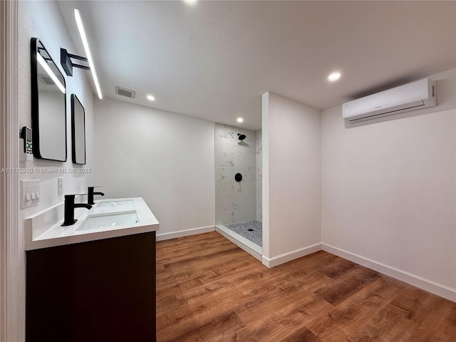 bathroom with a wall mounted air conditioner, hardwood / wood-style floors, vanity, and a tile shower