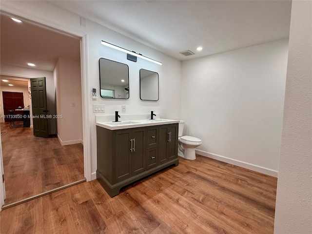 bathroom featuring wood-type flooring, vanity, and toilet