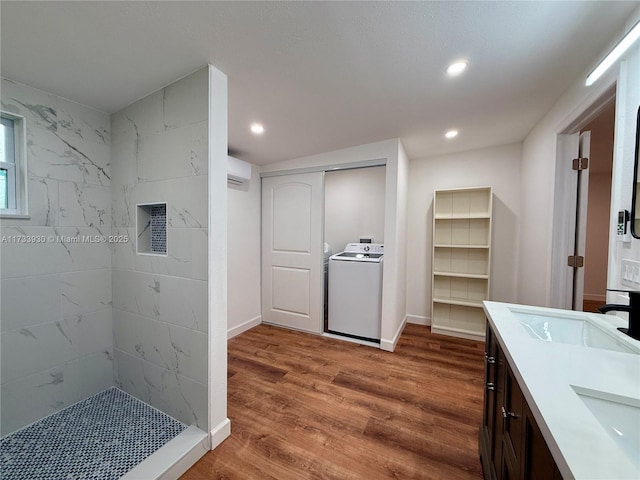 kitchen with sink, hardwood / wood-style flooring, dark brown cabinets, a wall mounted AC, and washer / clothes dryer