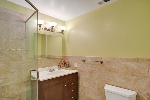 bathroom featuring vanity, toilet, and tile walls