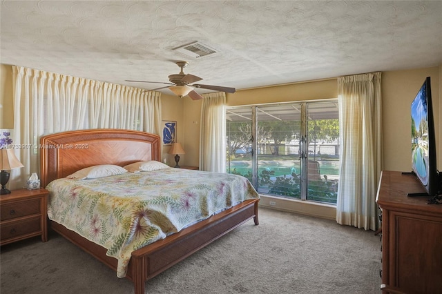 bedroom with ceiling fan, carpet floors, and a textured ceiling