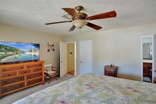 bedroom with ensuite bathroom, light colored carpet, a textured ceiling, and ceiling fan