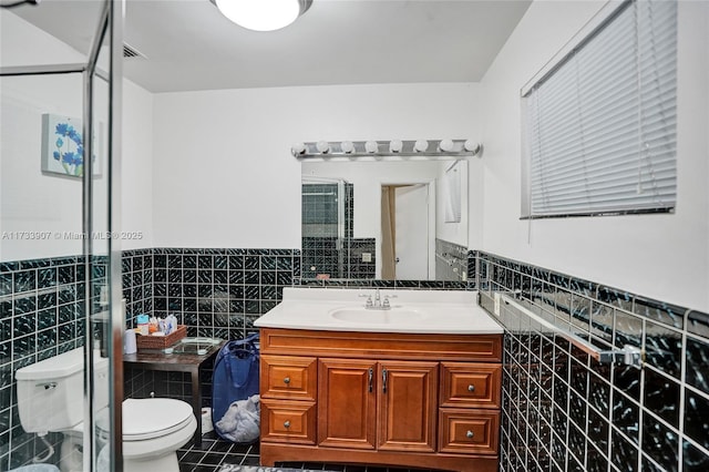 bathroom featuring walk in shower, toilet, tile walls, vanity, and tile patterned flooring