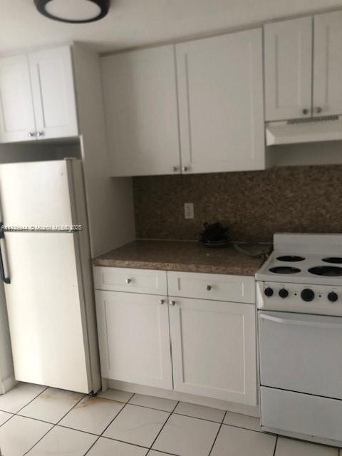 kitchen with light tile patterned flooring, white cabinets, white appliances, and decorative backsplash