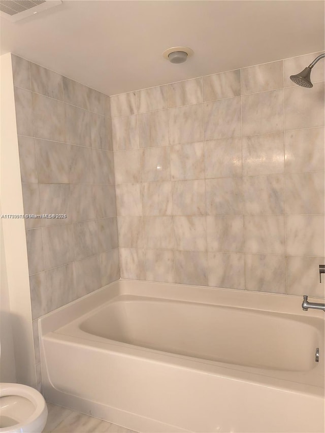 bathroom with tiled shower / bath and toilet