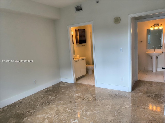 unfurnished bedroom with a sink, visible vents, ensuite bath, and baseboards