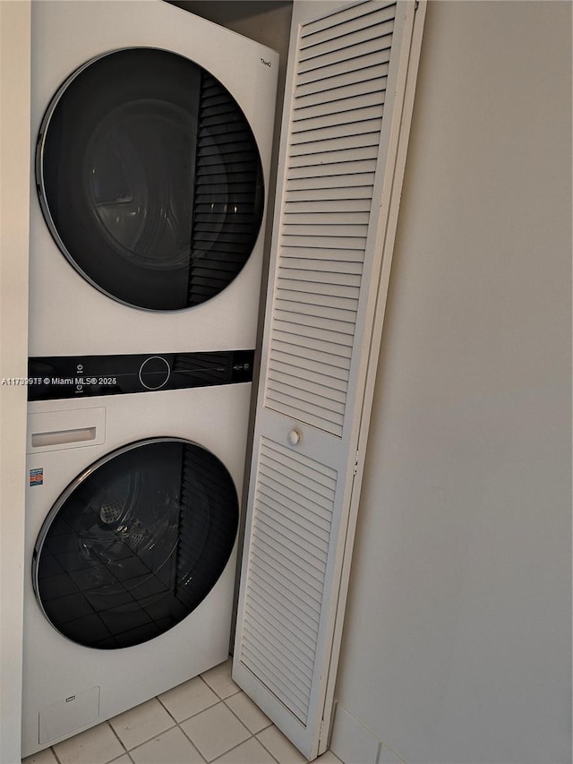 laundry room with light tile patterned floors, stacked washer and clothes dryer, and laundry area