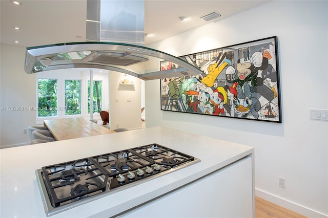 kitchen featuring island range hood, white cabinetry, light hardwood / wood-style flooring, gas stovetop, and french doors