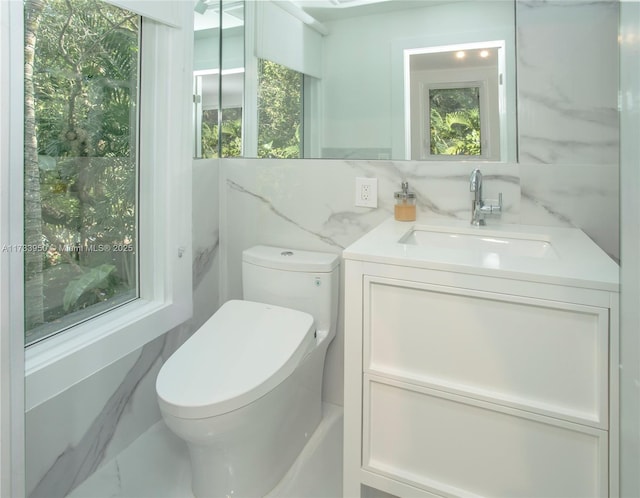 bathroom featuring vanity, toilet, and decorative backsplash