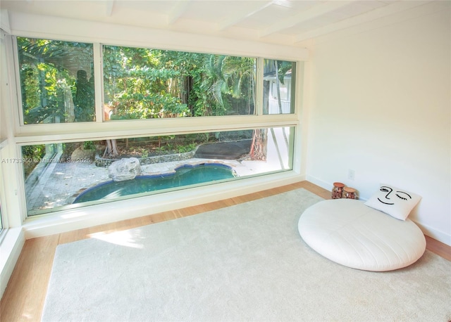 sunroom featuring beam ceiling and a wealth of natural light