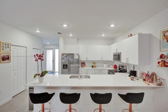 kitchen featuring light tile patterned flooring, appliances with stainless steel finishes, a breakfast bar, sink, and kitchen peninsula