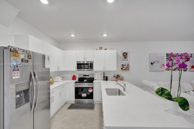 kitchen with stainless steel appliances, kitchen peninsula, sink, and white cabinets