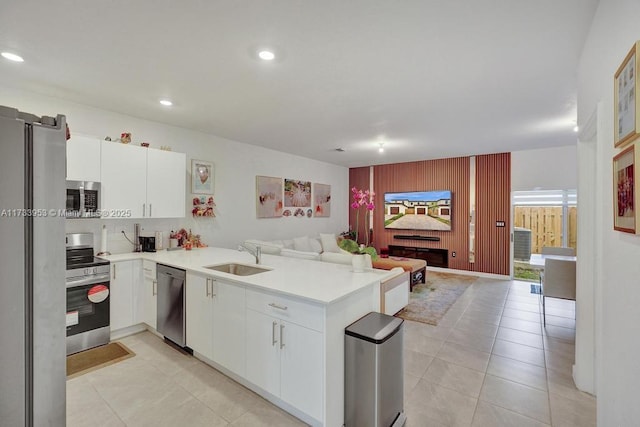 kitchen featuring sink, kitchen peninsula, white cabinets, and appliances with stainless steel finishes