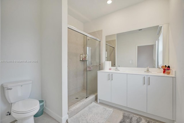 bathroom featuring vanity, a shower with door, tile patterned floors, and toilet