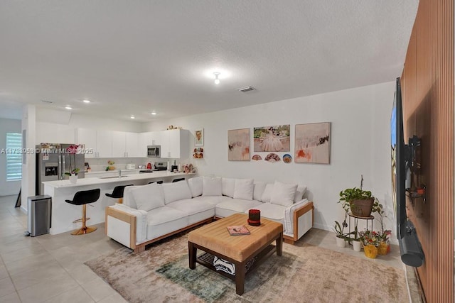 living room with sink, a textured ceiling, and light tile patterned floors