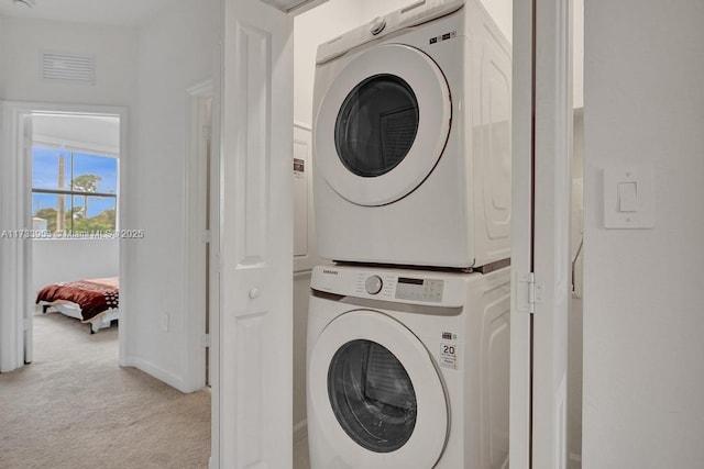 clothes washing area with stacked washer / dryer and light colored carpet