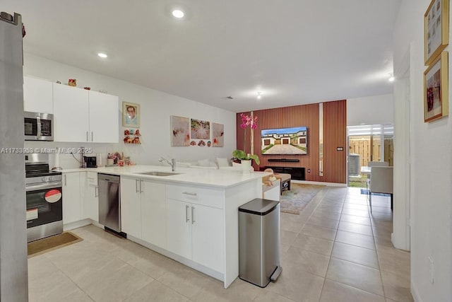 kitchen featuring white cabinetry, appliances with stainless steel finishes, kitchen peninsula, and sink