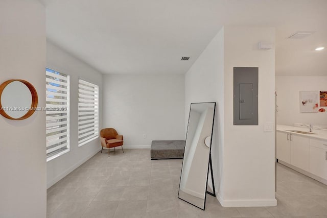 living area with electric panel, sink, and light tile patterned floors