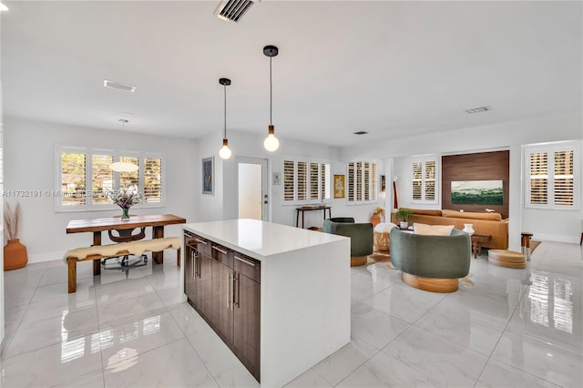 kitchen with decorative light fixtures, dark brown cabinets, and a kitchen island