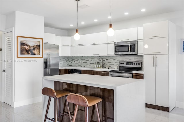 kitchen with tasteful backsplash, sink, a center island, and appliances with stainless steel finishes