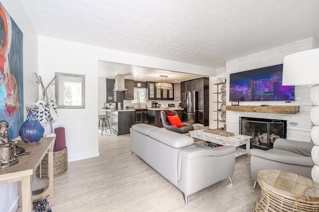 living room featuring a stone fireplace and light wood-type flooring