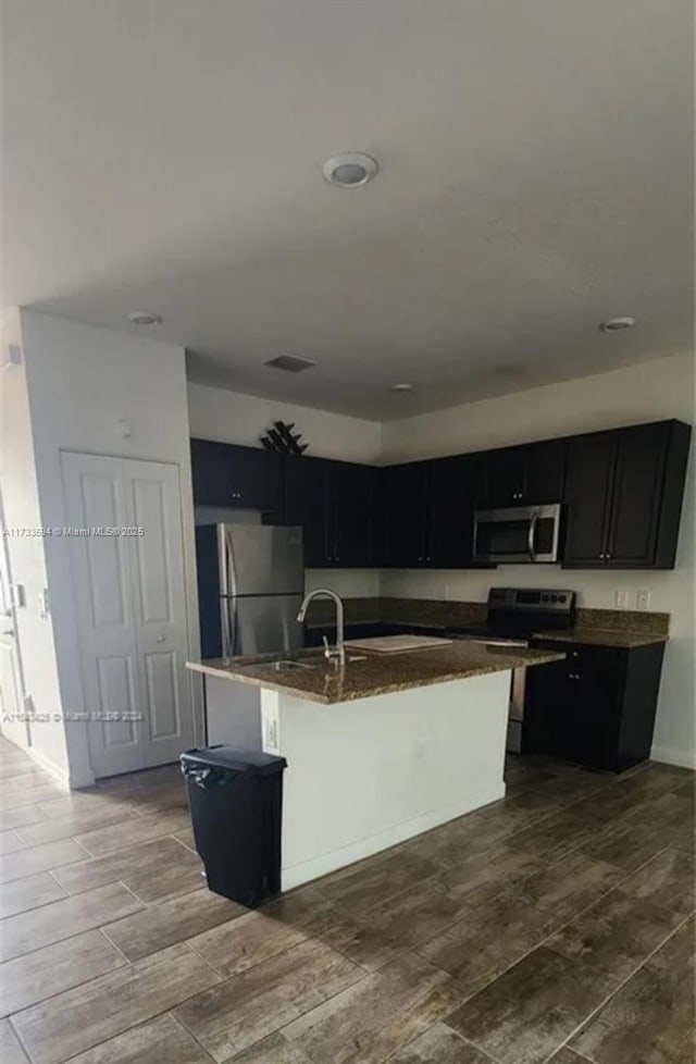 kitchen featuring sink, a kitchen bar, stainless steel appliances, and a center island with sink