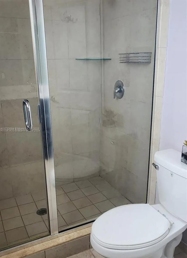 bathroom featuring a shower with door and toilet